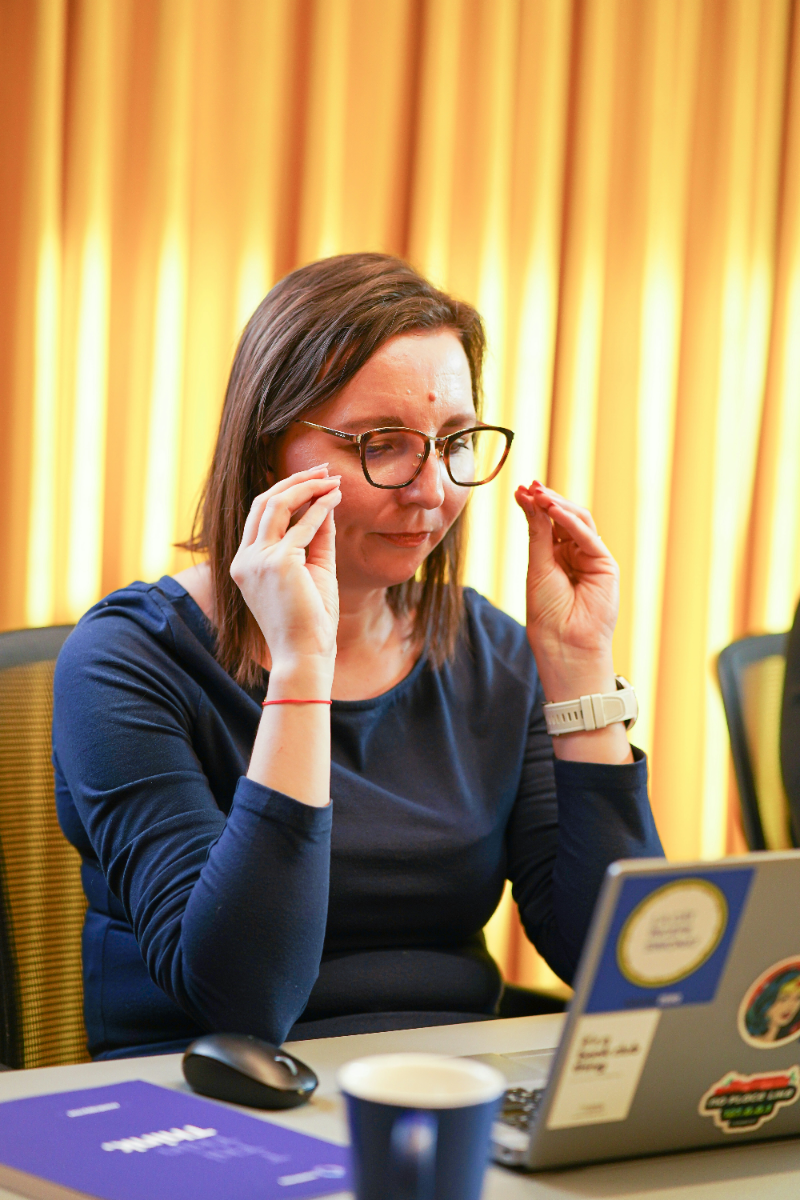 A woman thoughtfully adjusting her glasses, representing attention to detail and accuracy, highlighting how Conjoint and MaxDiff analysis can be applied.